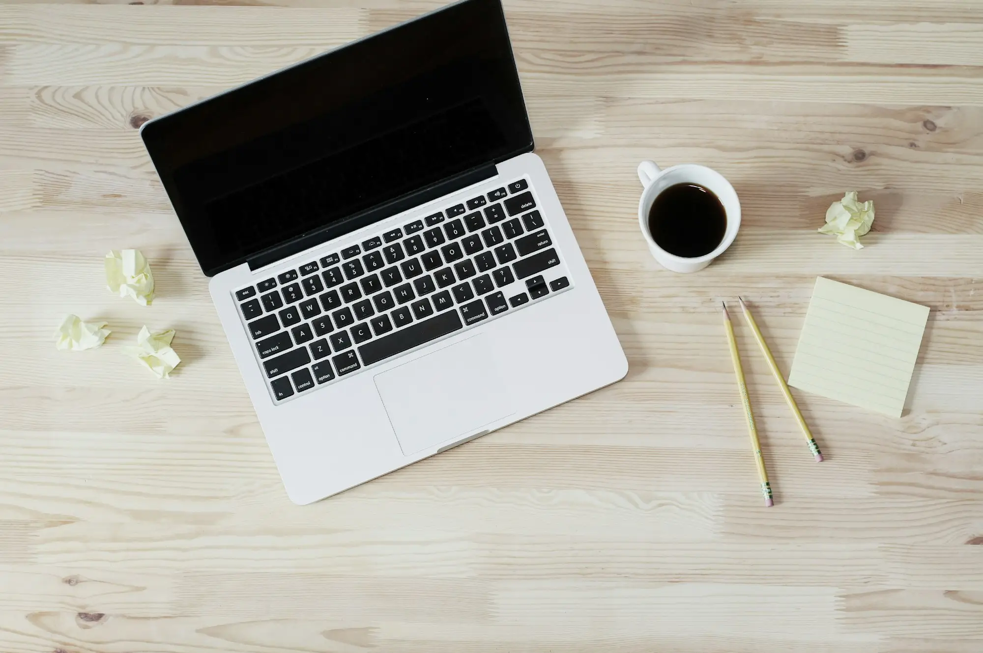 Laptop, notes and a coffee on a light timber desk