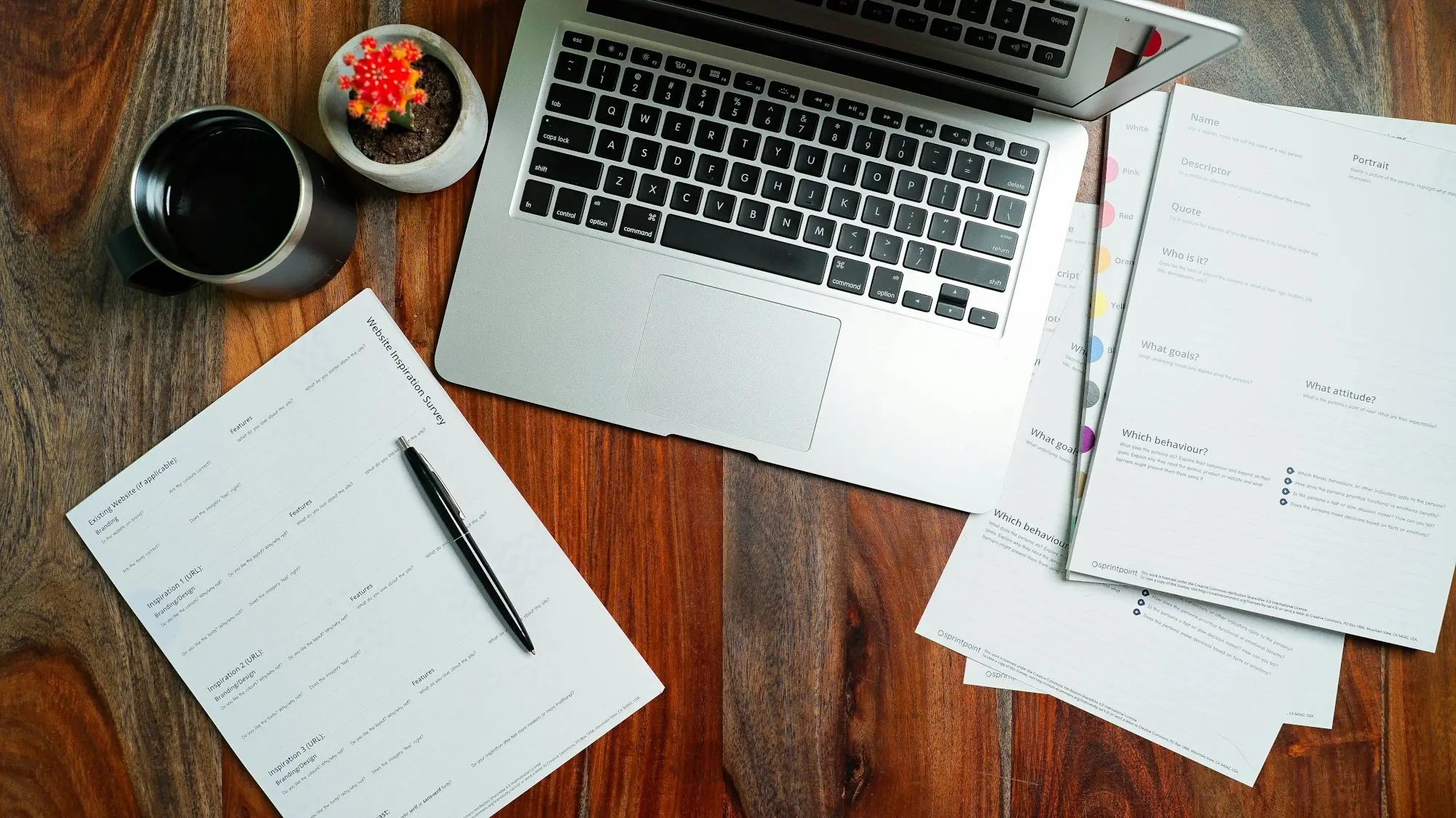 Printed report and pen beside a laptop on a timber desk