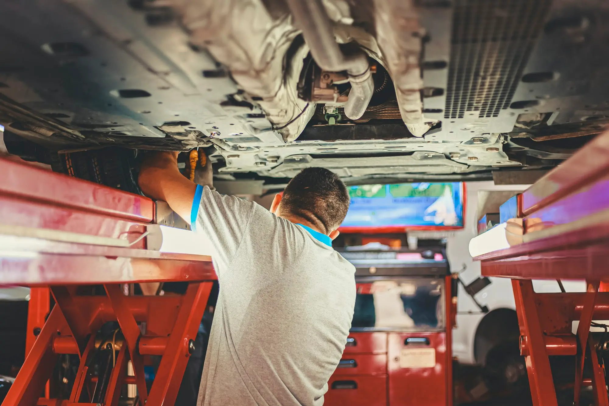 Mechanic working under a car on a hoist in a workshop