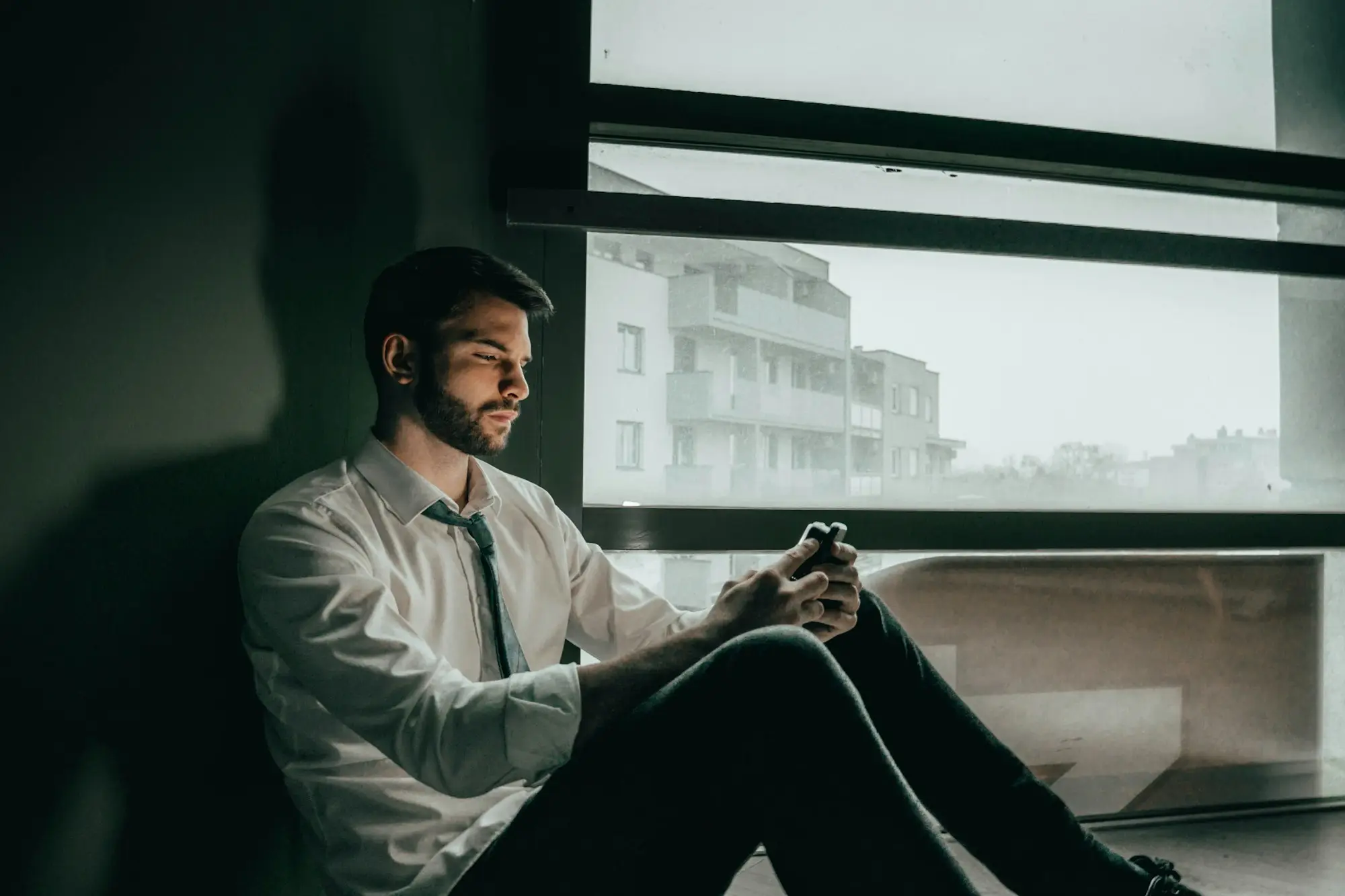 Man relaxing by a window while checking his phone