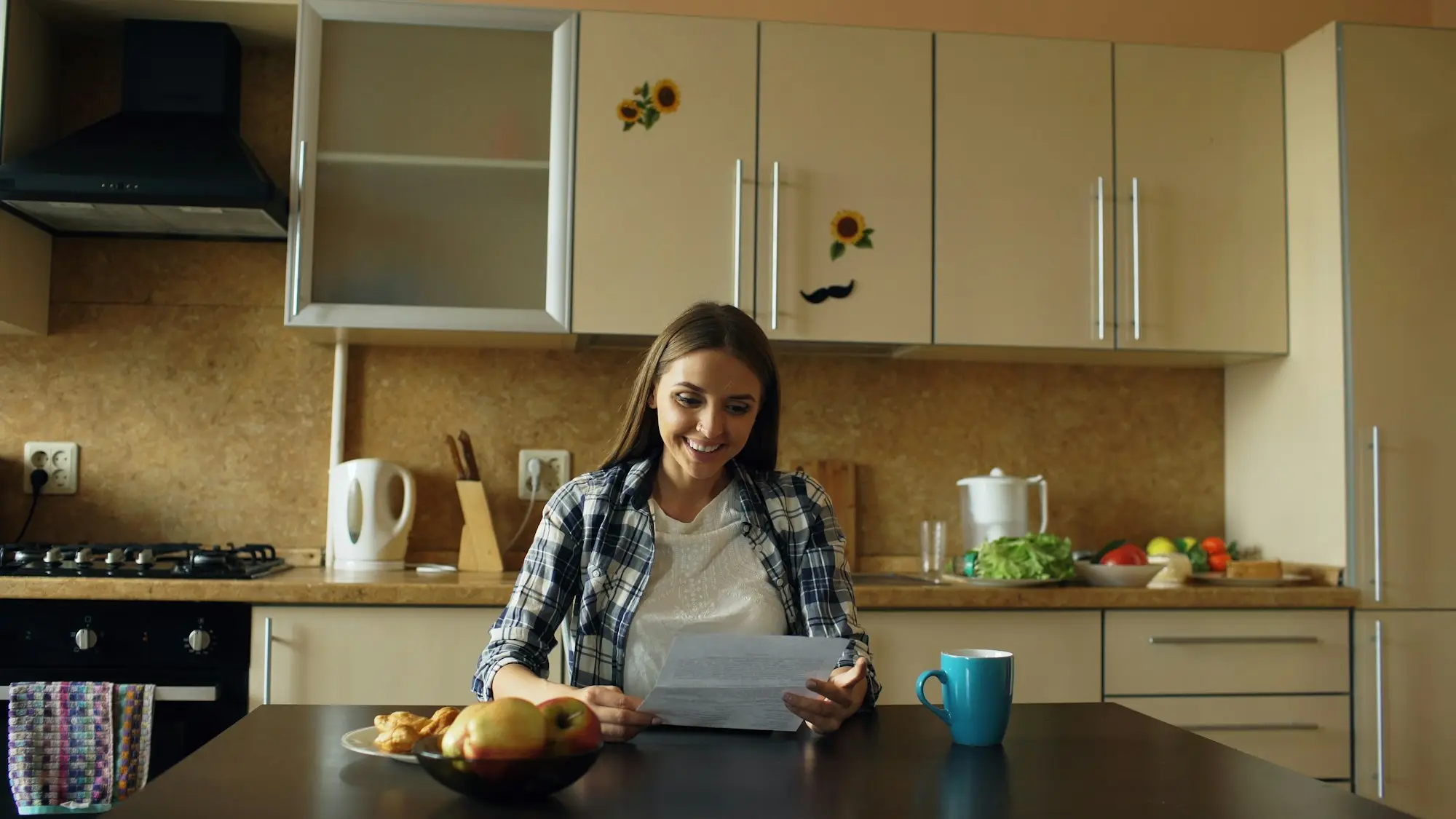 Business owner reading paperwork calmly at her kitchen table with a laptop